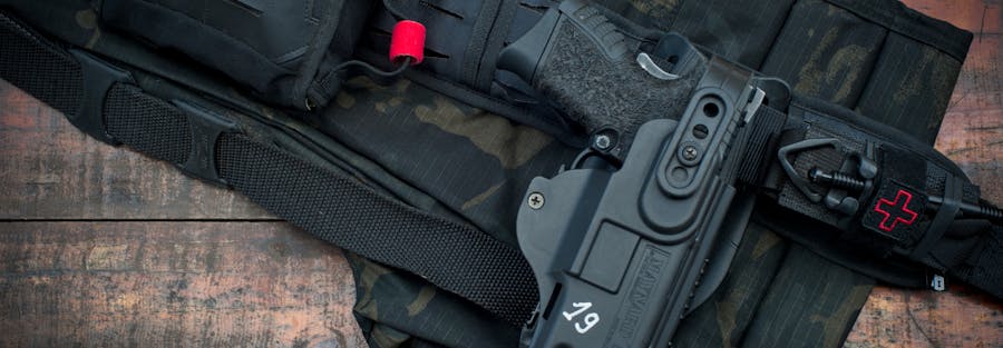 Close-up of tactical belt and handgun with camouflage pattern on wooden floor.